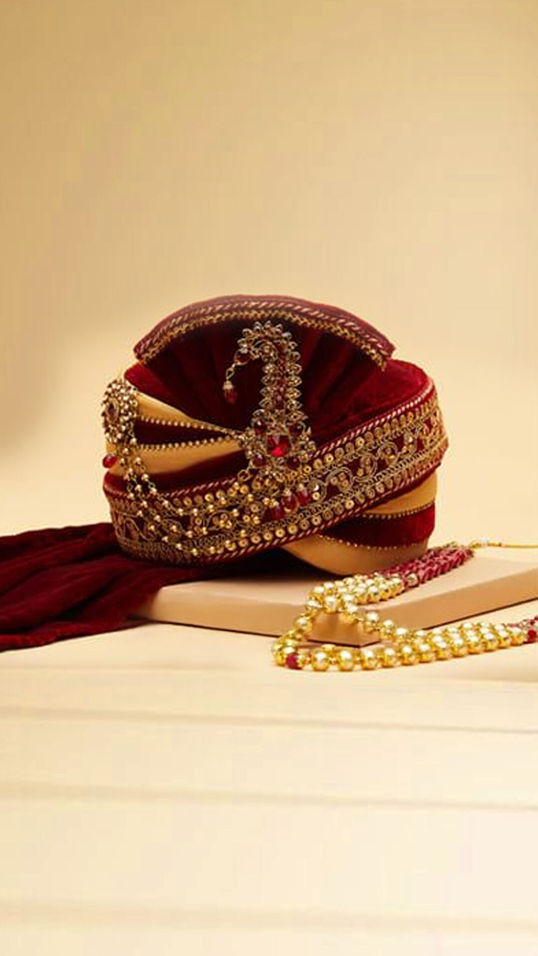 Luxurious red designer safa featuring a golden brooch, adding a royal touch to the groom's sherwani ensemble.